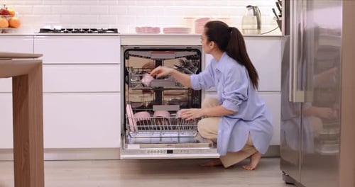 Woman Puts Plates Out Into Open Automatic Dishwasher Machine