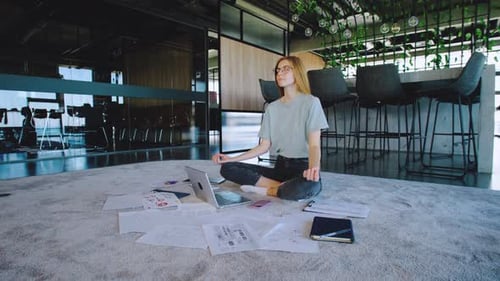Woman Meditating Amidst Paperwork in Modern Office