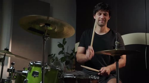Ein Mann spielt nachts Schlagzeug in einem Heimstudio, er sitzt hinter einem Schlagzeug und benutzt Drumsticks