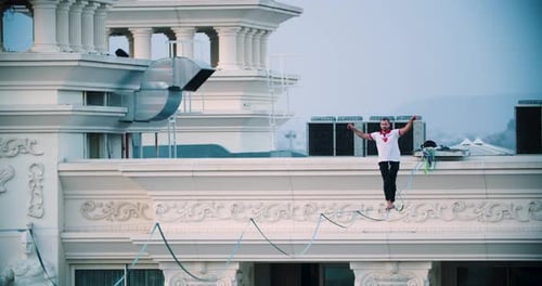 Man Balances on Tightrope Between Buildings