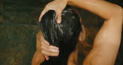 Woman Washing Long Hair with Shampoo in Shower