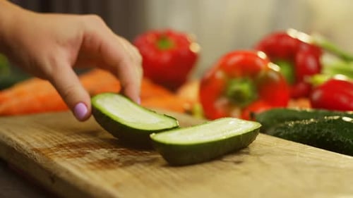 Woman Cutting Cucumber Into Slices on Wood Board
