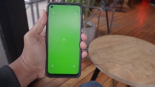 Person Holding Smartphone in a Cozy Cafe Setting