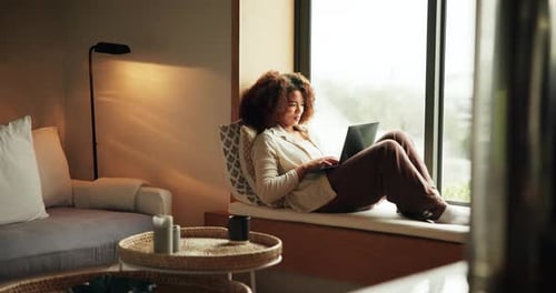 Woman with Laptop Relaxing on Window Seat at Home