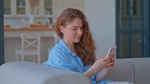 Woman Using a Smartphone on Couch Indoors