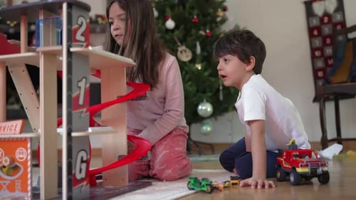 Girl and Boy Playing with Toy Garage at Home