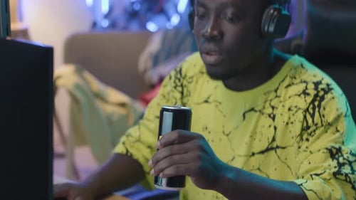 Young Black Gamer Playing and Drinking Energy Beverage