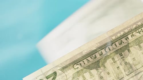 Close-up, twenty-dollar bills falling onto a glass table. View from below.