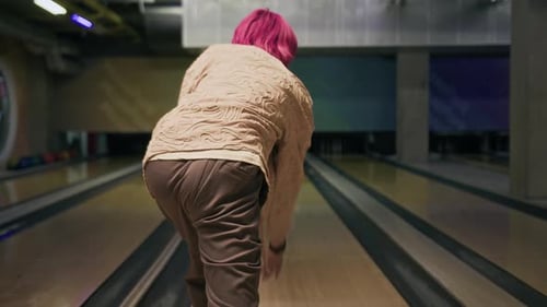 Asiatischer Typ mit rosa Haaren wird beim Bowling mit Freunden geschlagen
