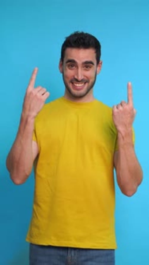 Happy Man with Yellow Shirt Pointing at Empty Space