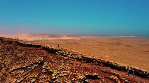 Unrecognizable Tourists Walk Along Edge of Crater Ridge