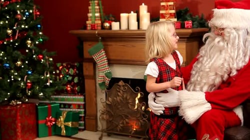 Girl with Santa Claus receiving Christmas gift indoor