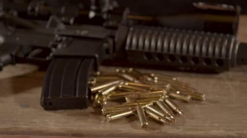 Wide dolly out of AR-15 with a lot of ammunition lying on wooden surface