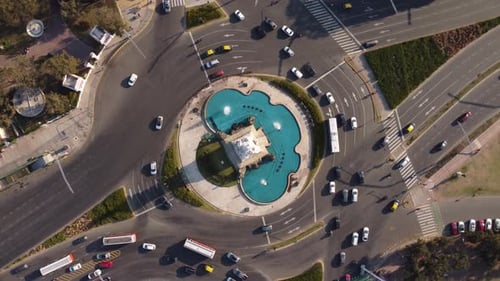 Aerial top down showing spraying fountain of La Carta Manga Monument with driving cars at roundabout