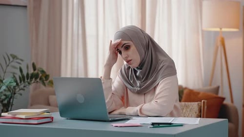 Woman Works on Computer and Rubs Face with Fingers Tiredly