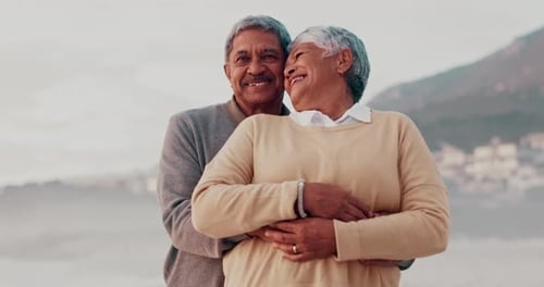 Love, hug and happy senior couple at the beach bond, laugh and embracing freedom together