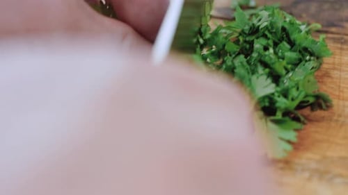 a Woman's Hand Cuts Green Onions with a Knife on a Wooden Chopping Board Slicing Greens for Salad