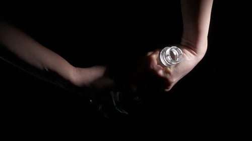 Hands Crushing Clear Plastic Bottle on Black Background