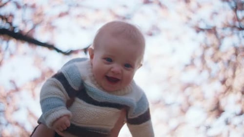 Happy Mother Lifts Her Baby High