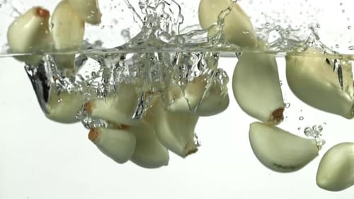 Los dientes de ajo caen bajo el agua filmados con una cámara de alta velocidad a 1000 fps