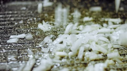 Chopped Onions Being Poured onto Oily Grill