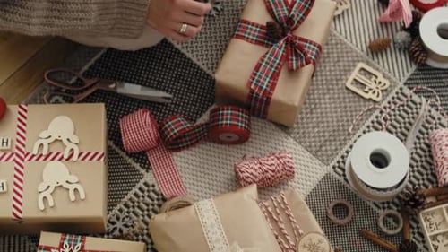 Top view of unrecognizable caucasian woman wrapping Christmas gifts on the floor. Shot with RED heli