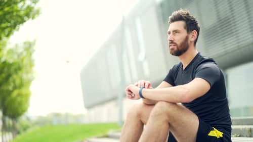 Man Sits on Steps Using Smart Watch