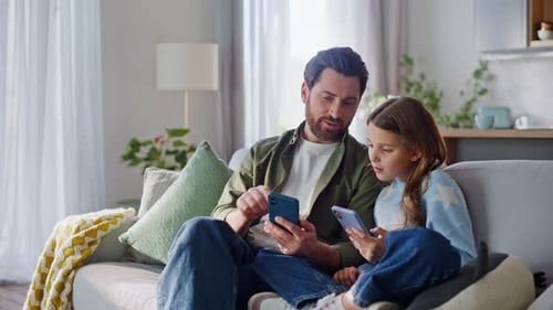 Dad and Girl on Couch Using Mobile Phones