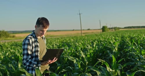 Junger Landwirt arbeitet mit einem Laptop auf einem malerischen Feld