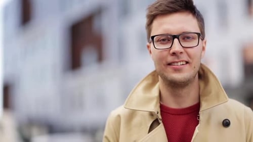 Happy young man smiling outdoors wearing eyeglasses in the city