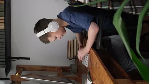 Teen with Headphones Using Keyboard at Wooden Desk