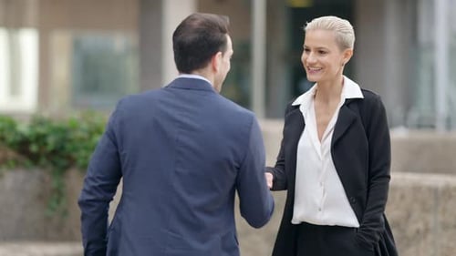 Businesswoman and Businessman Shaking Hands in the City Street