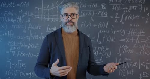 Teacher Explains Math in Front of Blackboard