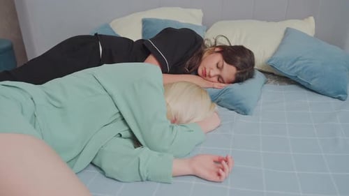 Women Sleeping Peacefully on Bed with Blue Pillows in Cozy Bedroom