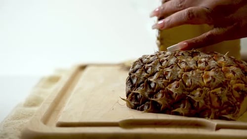 Woman Slices Pineapple on Cutting Board