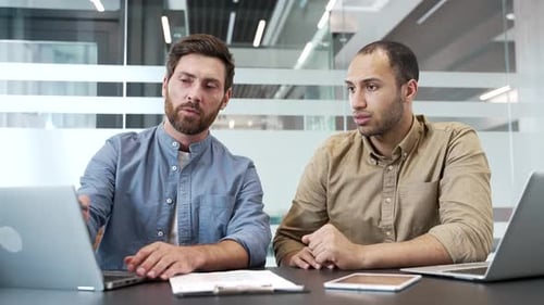Two businessmen are engaged in brainstorming, communicate using laptop in business office.