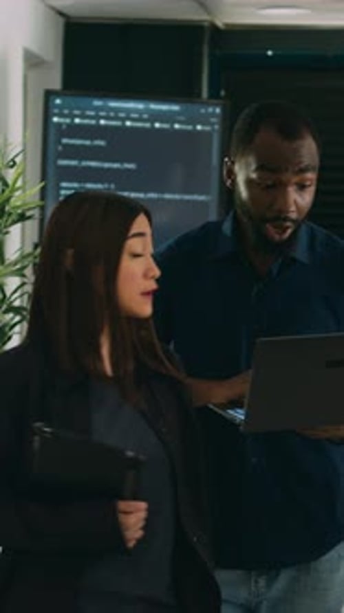 Vertical Video Two Software Coders Analyzing Source Code Looking for Errors on Laptop