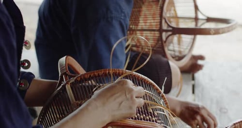 Deux agricultrices thaïlandaises tissent des paniers selon des motifs d'art thaïlandais traditionnels