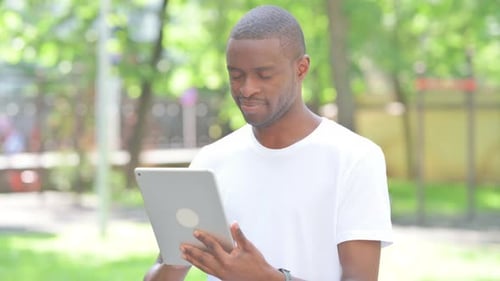 Portrait of African Man Using Digital Tablet Outdoor in Park