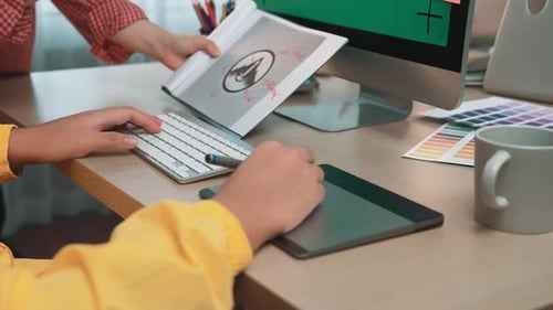 Creative workspace with hands using graphic tablet, keyboard, and computer for d