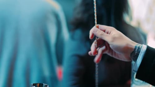 Bartender stirs a cocktail drink with bar spoon