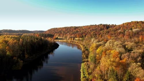 Autumn foliage reflecting on a serene river in a tranquil landscape