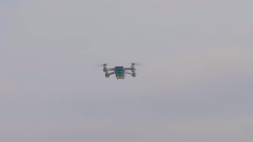 A closeup view of a flying drone camera, blinking lights and turning.
