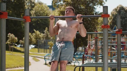 Athletic Caucasian Topless Muscular Man Doing Pull Ups Exercises on Horizontal Bar Pumping Up Back