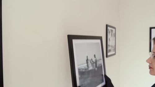 Female Gallery Worker Putting Framed Photo on Wall
