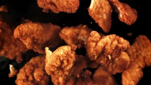Fried Chicken Pieces Floating on Black Background