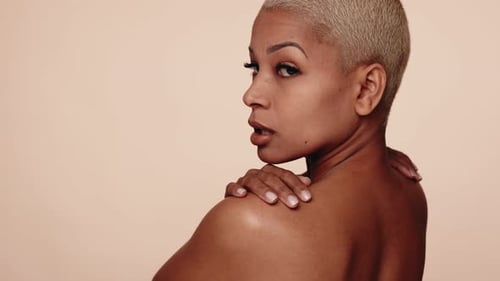 Femme confiante aux cheveux courts posant par-dessus l'épaule