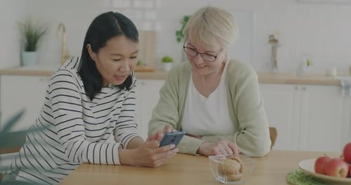 Adult and Senior Look at Smartphone in Kitchen