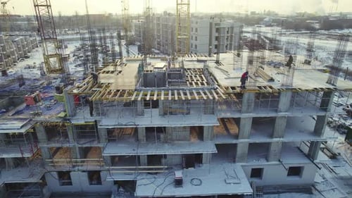 Baufortschritt auf einer Großbaustelle im Winter mit Kränen und Arbeitern im Einsatz