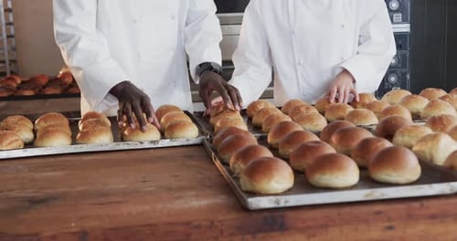 Happy diverse bakers working in bakery kitchen, counting fresh rolls in slow motion